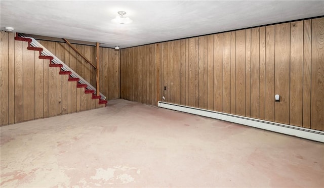 finished basement featuring a baseboard radiator, stairs, and wood walls