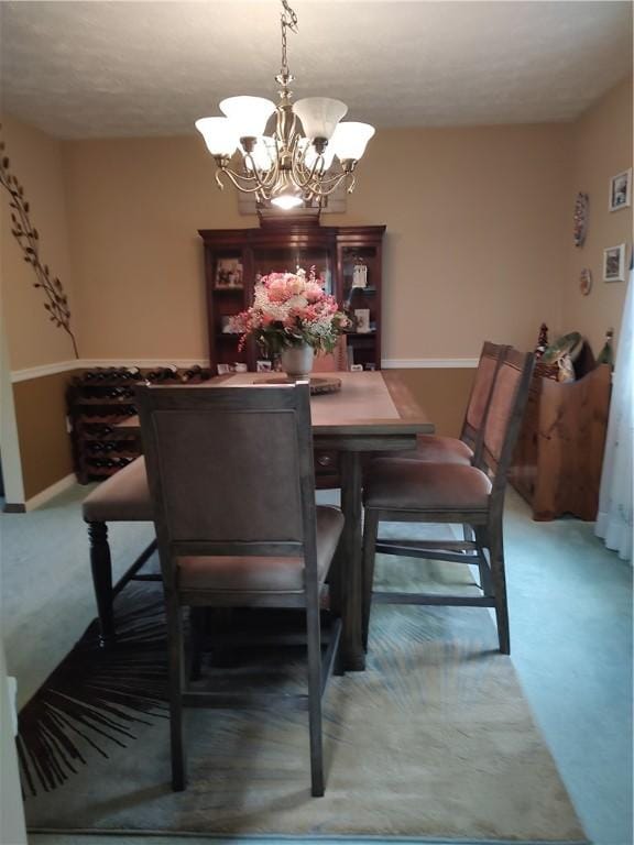 dining space with light colored carpet, a chandelier, and baseboards