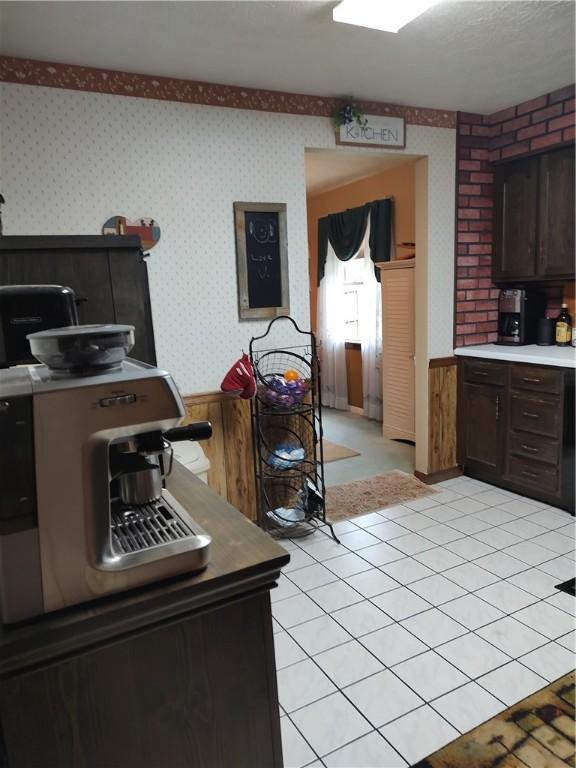 100 Forest Dr, Natrona Hts/Harrison Twp, PA 15065 - kitchen with wallpapered walls, a wainscoted wall, dark brown cabinetry, and light countertops