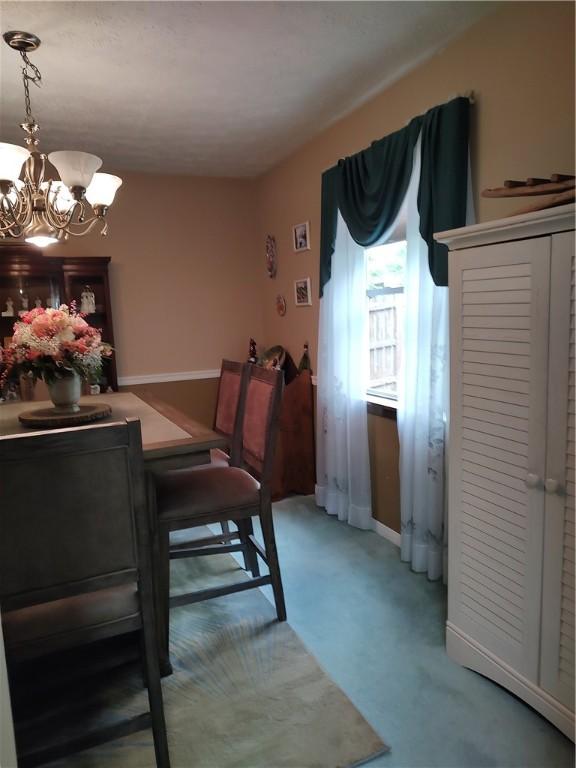 dining area featuring a chandelier, light carpet, and baseboards