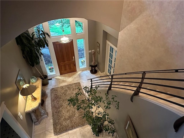 tiled entrance foyer featuring arched walkways, baseboards, and a high ceiling