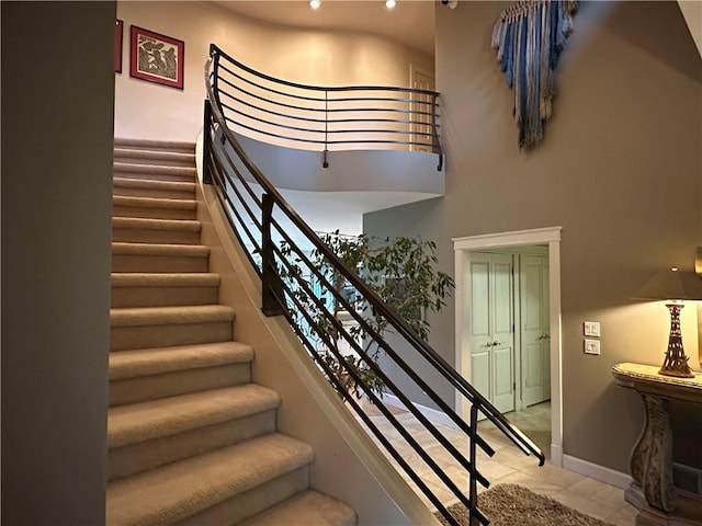 stairs with baseboards, tile patterned flooring, and a towering ceiling