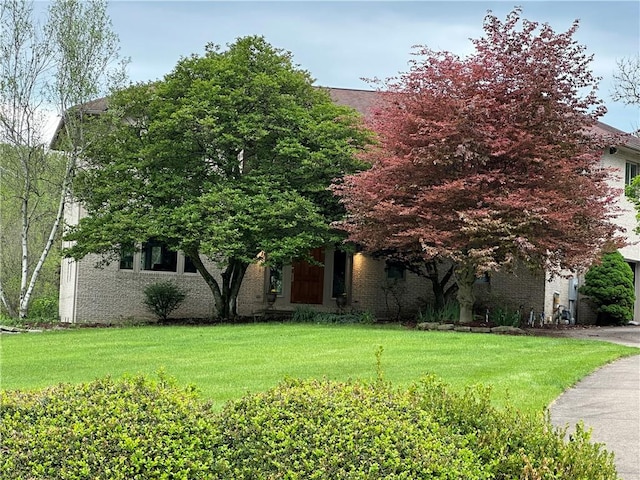obstructed view of property featuring a front lawn and brick siding