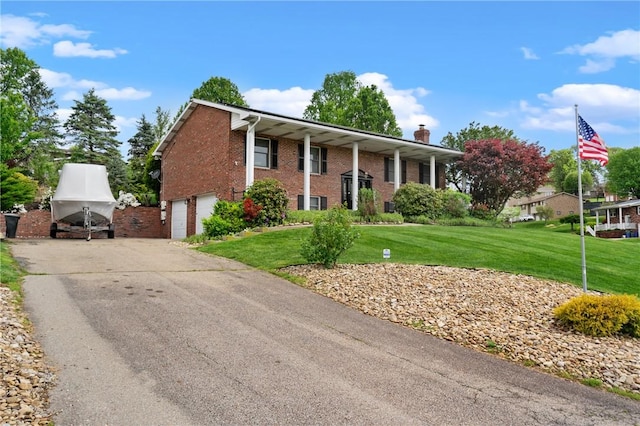 bi-level home featuring driveway, a chimney, a front yard, a garage, and brick siding