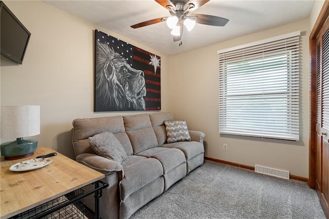 carpeted living room with baseboards, ceiling fan, and visible vents