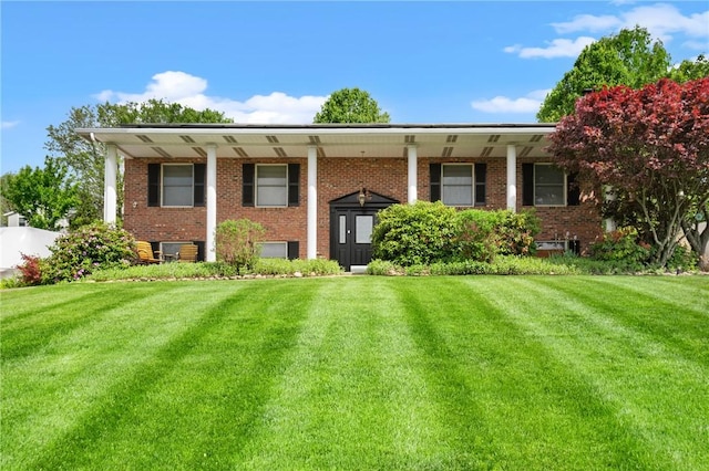 raised ranch with brick siding and a front yard