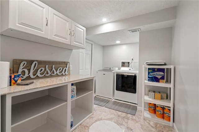 washroom featuring washer and dryer, laundry area, a textured ceiling, marble finish floor, and visible vents