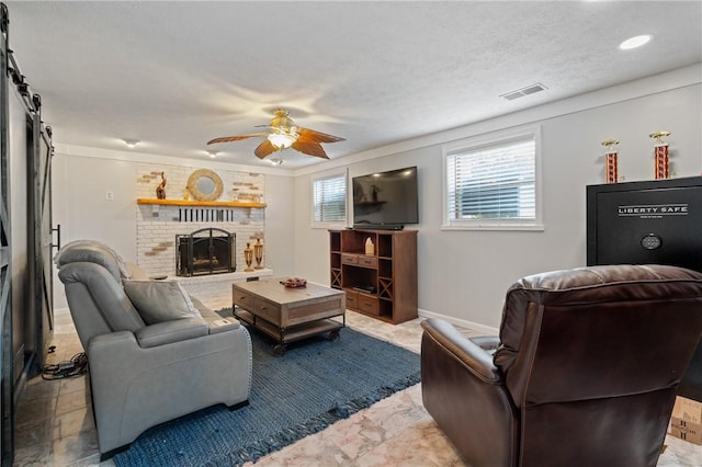living area featuring a barn door, marble finish floor, a ceiling fan, baseboards, and visible vents