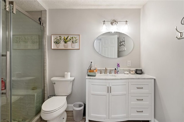 bathroom featuring a textured ceiling, a shower stall, vanity, baseboards, and toilet
