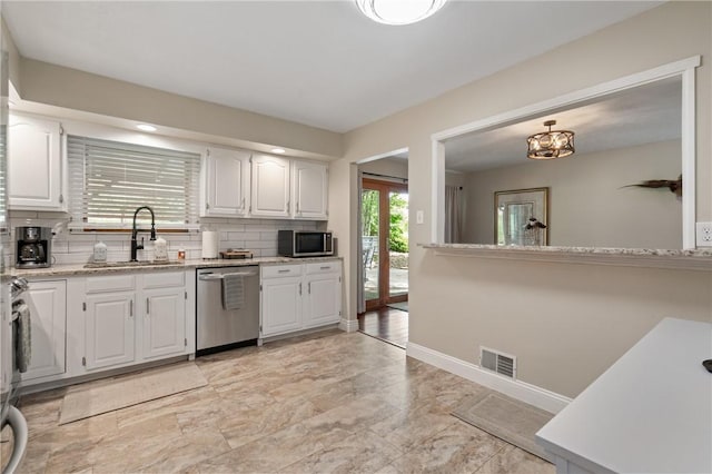 kitchen with white cabinets, appliances with stainless steel finishes, a sink, decorative backsplash, and visible vents