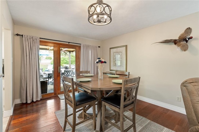 dining area featuring baseboards, a notable chandelier, and wood finished floors
