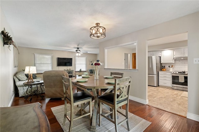 dining area with baseboards, wood finished floors, and ceiling fan with notable chandelier