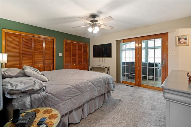bedroom featuring a ceiling fan, visible vents, two closets, access to outside, and carpet flooring
