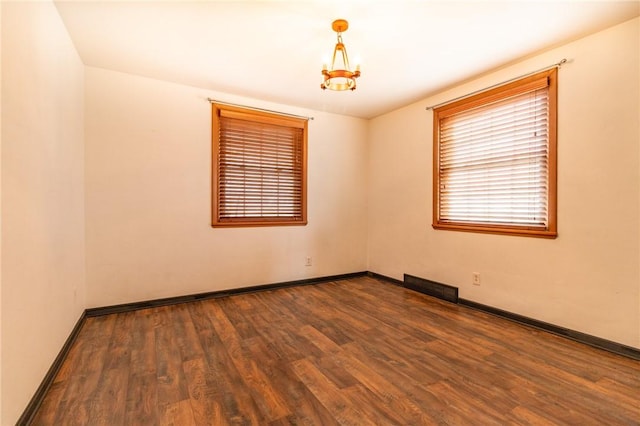 empty room with visible vents, baseboards, and wood finished floors