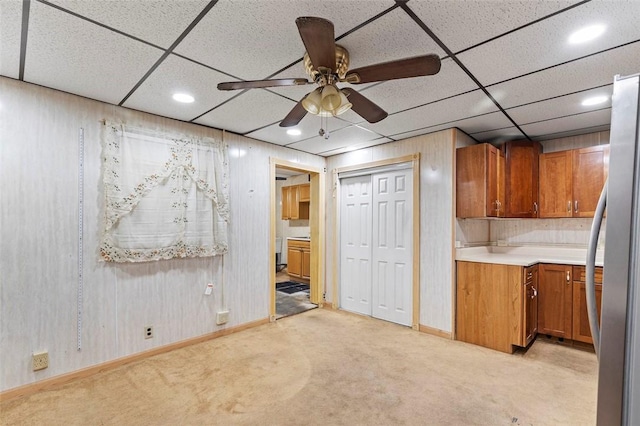 below grade area with freestanding refrigerator, a ceiling fan, baseboards, and light carpet