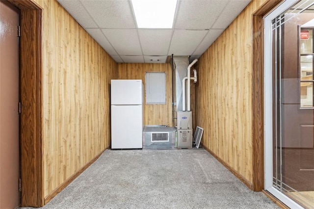 unfurnished room with wooden walls, baseboards, carpet floors, and a paneled ceiling