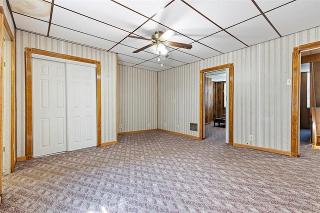 unfurnished bedroom featuring carpet floors, a ceiling fan, baseboards, wallpapered walls, and a closet