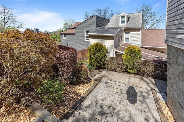 exterior space featuring fence, a shingled roof, and a patio area