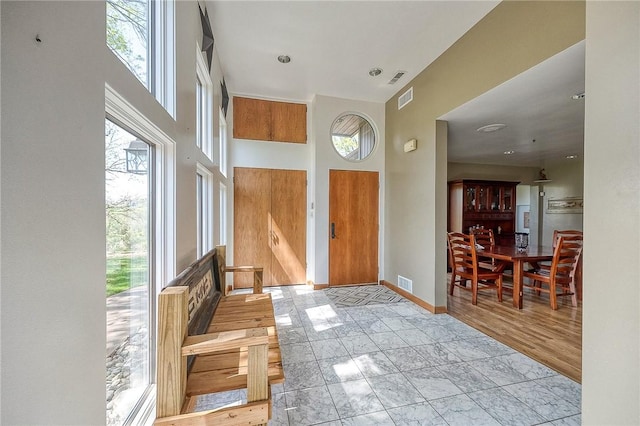 entryway featuring baseboards, a high ceiling, and visible vents
