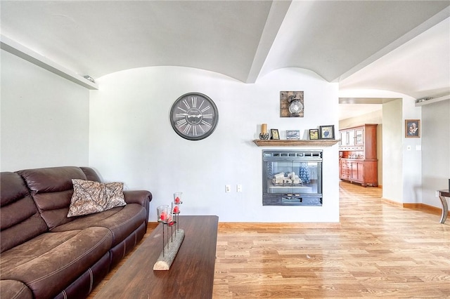 living area featuring baseboards, vaulted ceiling, and light wood finished floors