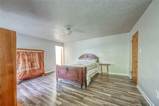bedroom with baseboards, a textured ceiling, and wood finished floors