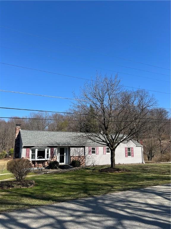 single story home with a chimney and a front yard