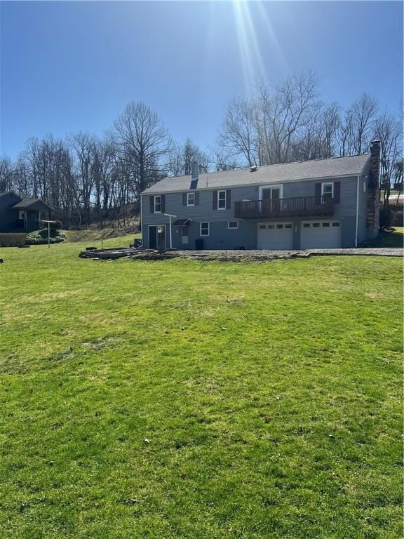 back of house featuring an attached garage, a yard, and a chimney