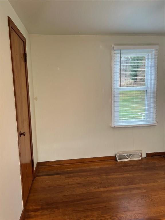 unfurnished room with baseboards, visible vents, and wood finished floors