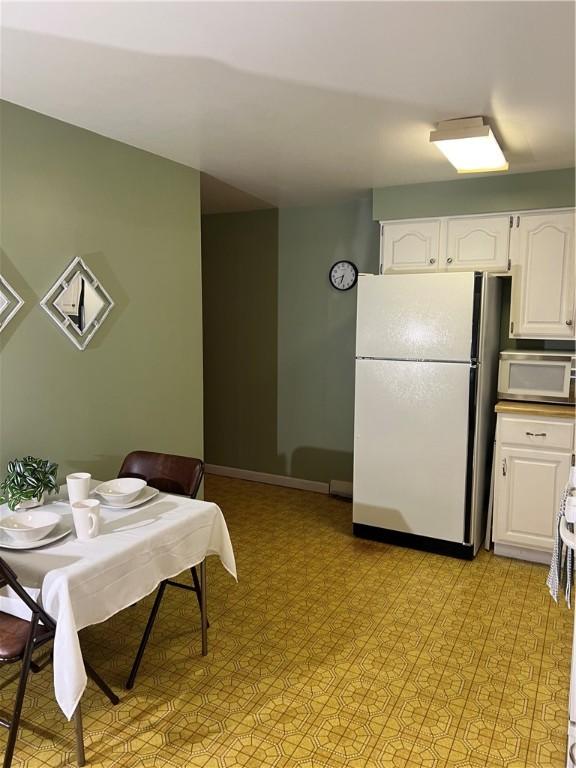 dining space featuring baseboards and light floors