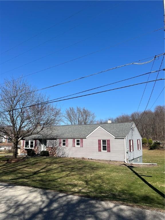 ranch-style house with roof with shingles and a front lawn
