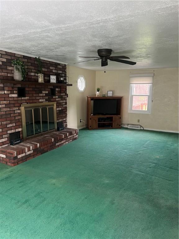 unfurnished living room with a ceiling fan, a textured ceiling, a fireplace, baseboards, and carpet