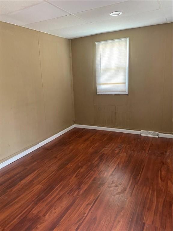 empty room featuring baseboards, dark wood-style flooring, and visible vents