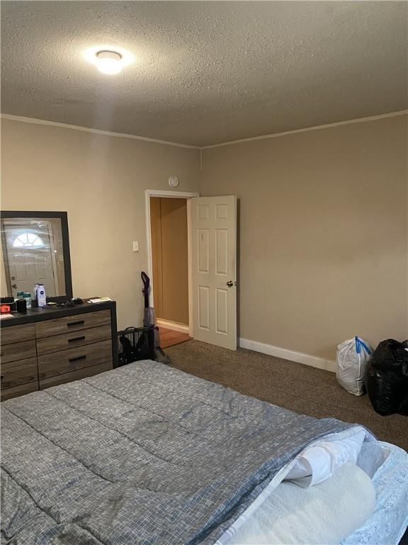 bedroom with carpet floors, a textured ceiling, crown molding, and baseboards