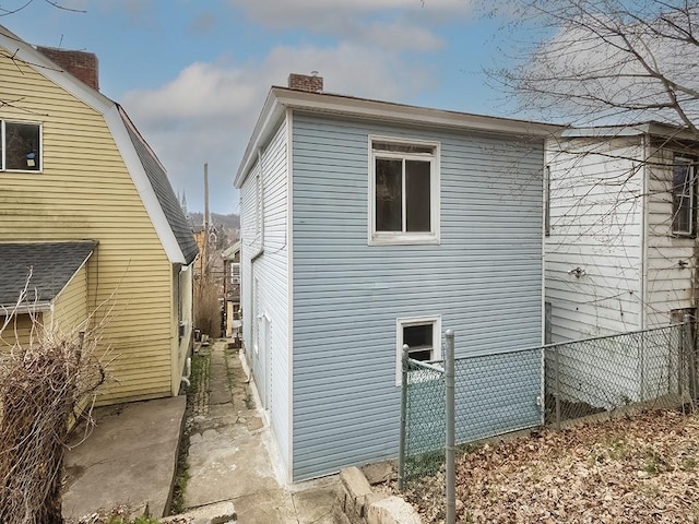 view of property exterior featuring fence and a chimney