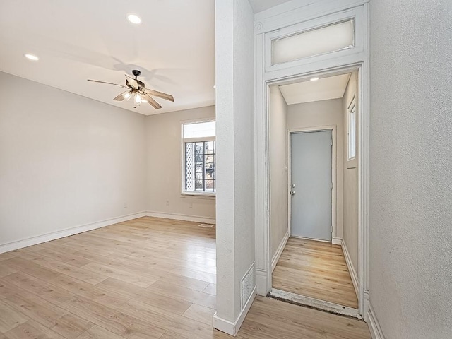 corridor with baseboards, recessed lighting, light wood-style flooring, and a textured wall