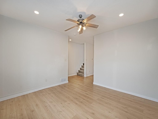 spare room with baseboards, ceiling fan, light wood-style flooring, and visible vents