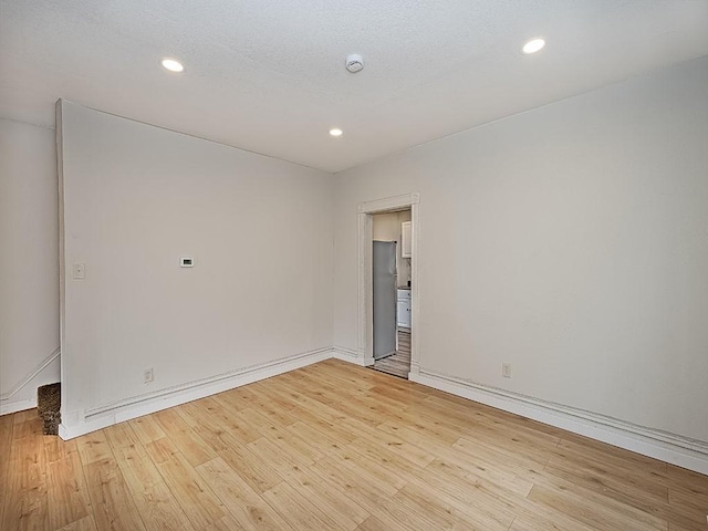 empty room featuring baseboards, recessed lighting, and light wood-style flooring