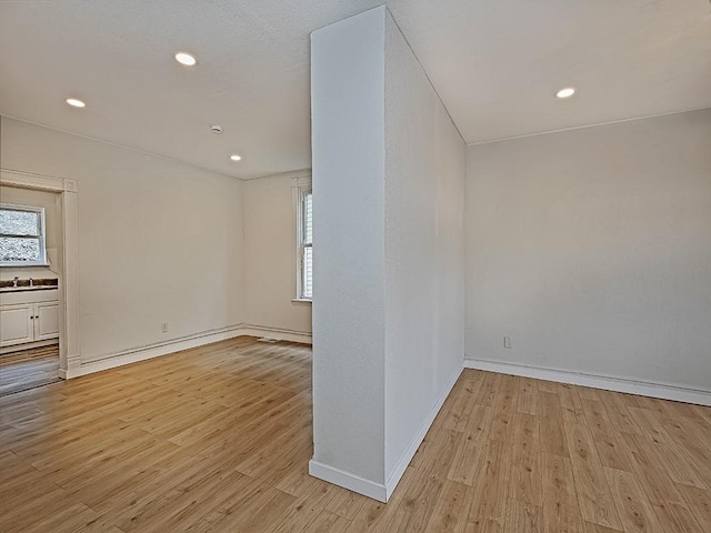 empty room featuring recessed lighting, baseboards, and light wood finished floors