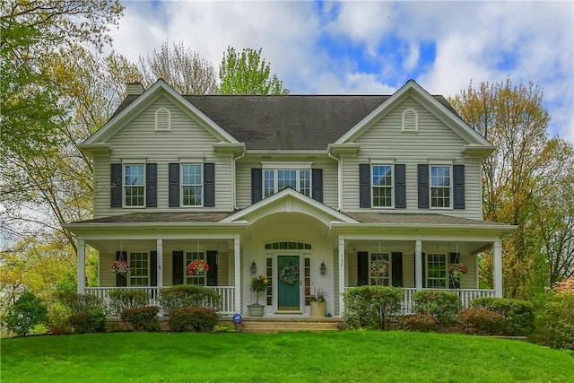 view of front of home featuring covered porch, a chimney, and a front lawn