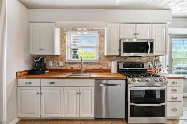 kitchen featuring a sink, appliances with stainless steel finishes, tasteful backsplash, and wooden counters