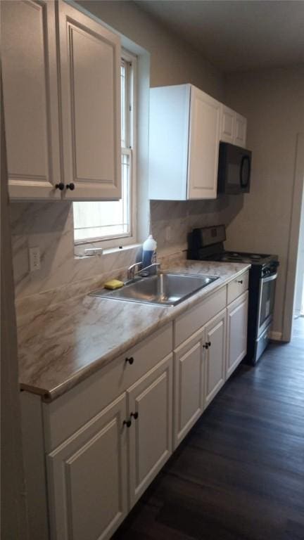 kitchen featuring dark wood-style flooring, black microwave, stainless steel gas stove, a sink, and white cabinets