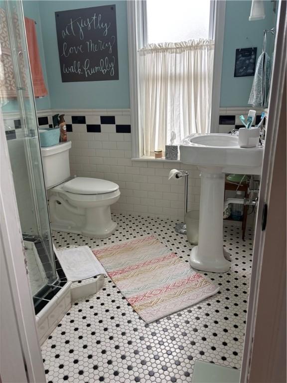 full bath featuring a wainscoted wall, a stall shower, and a wealth of natural light