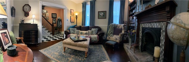 living area featuring stairs, a brick fireplace, and wood finished floors