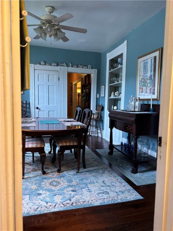 dining room featuring ceiling fan, wood finished floors, and built in shelves