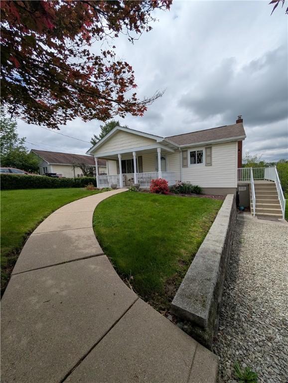 view of front of home with stairs, a chimney, a porch, and a front yard