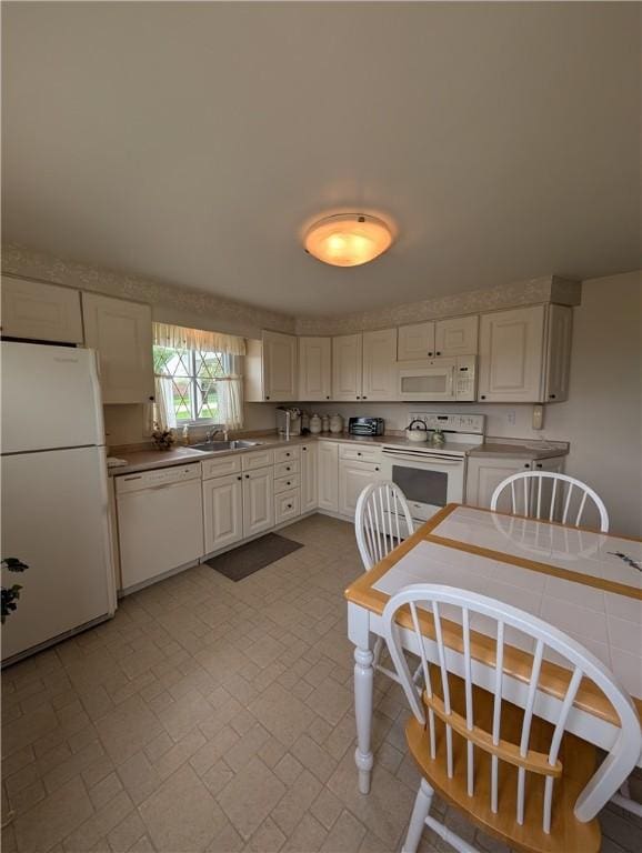 kitchen featuring a sink, white cabinets, and white appliances