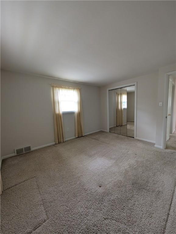 interior space with baseboards, light carpet, and visible vents