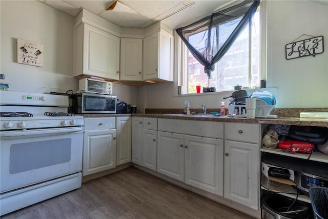 kitchen with white cabinets, white range with gas cooktop, a sink, and light wood-type flooring