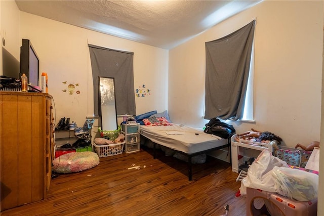 bedroom with a textured ceiling and wood finished floors