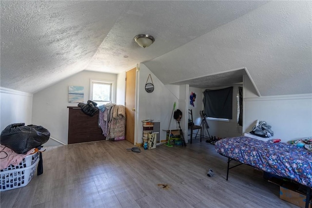 bedroom with a textured ceiling, wood finished floors, and lofted ceiling